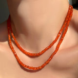 2 faceted carnelian gemstone necklaces layered on a model's neck.