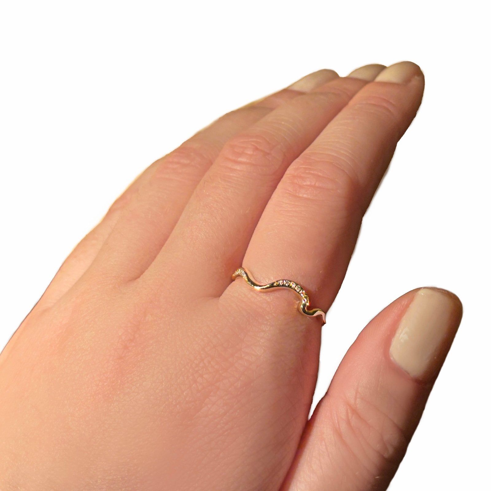 A gold band ring with a wavy design featuring small diamonds, displayed on a hand.