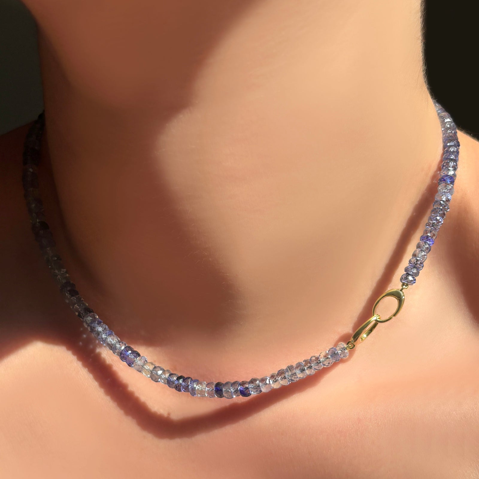 Denim blue faceted sapphire necklace with 14K gold linking ovals clasp to the front.