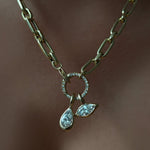 A diamond cut link chain fastened with a round pavé face charm lock, securing two molten solitaire charms, one pear, one marquise.
