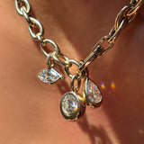 Drop link chain necklace with triple link charm lock holding molten solitaire charms with round, pear, and marquise diamonds on the neck.