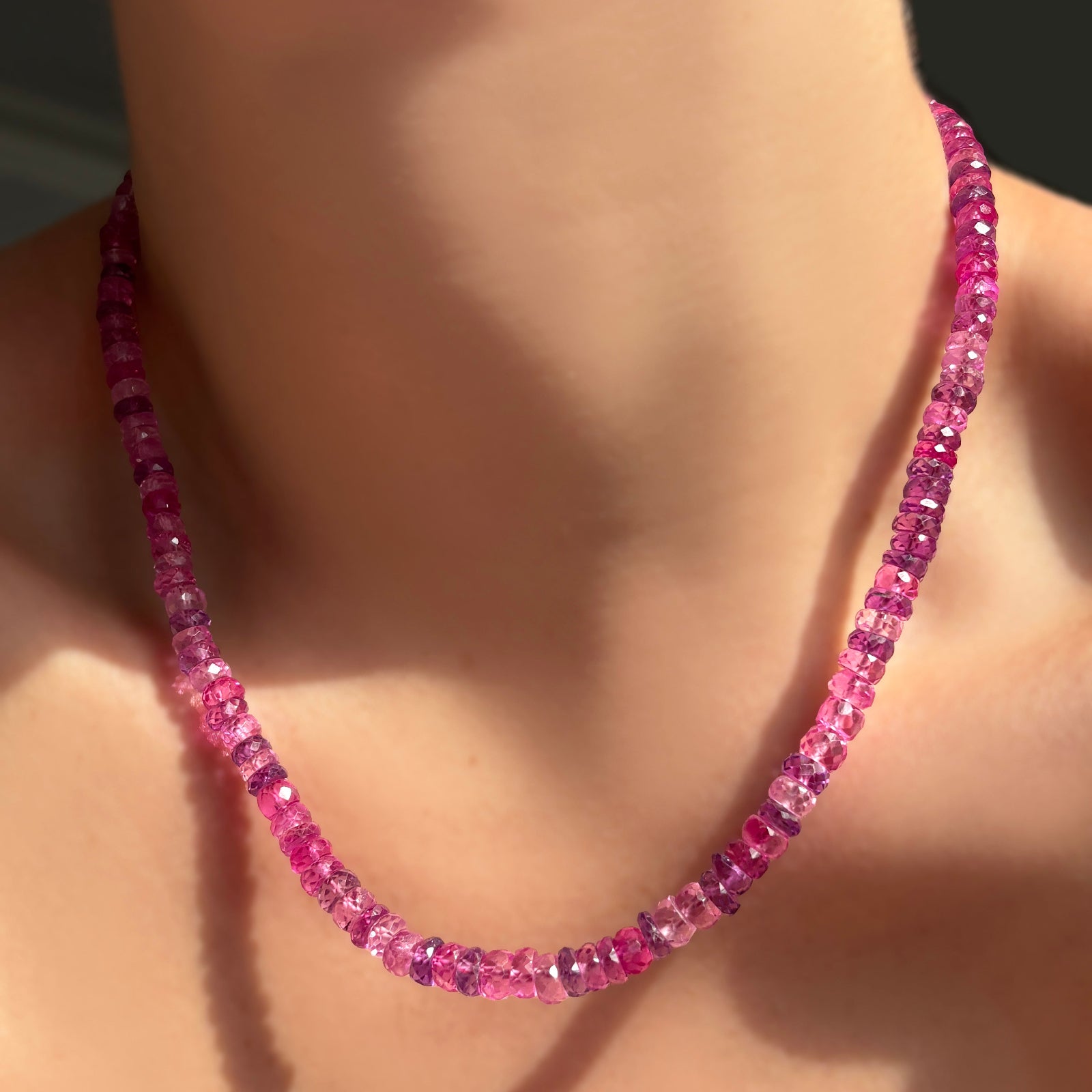 Fuchsia faceted sapphire necklace on a model's neck.