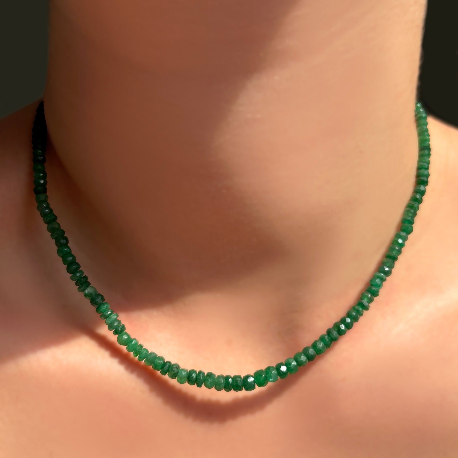 A single AMANDA PEARL green faceted emerald necklace on a model's neck.