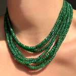 green faceted emerald necklaces layered on a model's neck.
