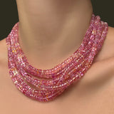 Multiple AMANDA PEARL hibiscus sapphire necklaces layered on a model's neck.