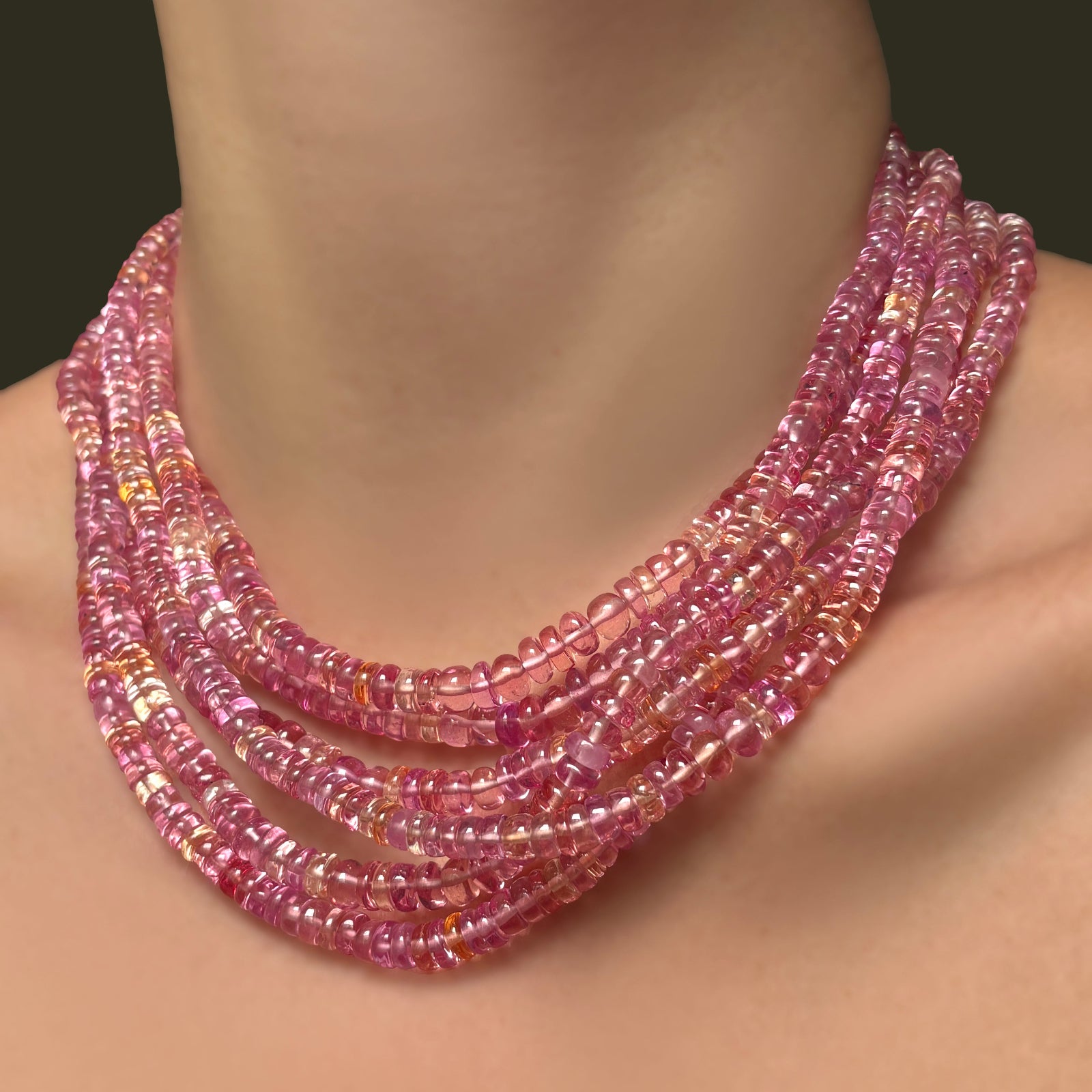 Multiple AMANDA PEARL hibiscus sapphire necklaces layered on a model's neck.