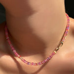 An AMANDA PEARL hibiscus sapphire necklace with its 14k gold Evolution Clasp turned toward the front.