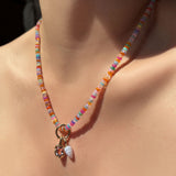 High-biscus opal necklace with beaded round charm lock, molten knot charm with amethyst, and blue lace agate drop charm hanging from the neck.
