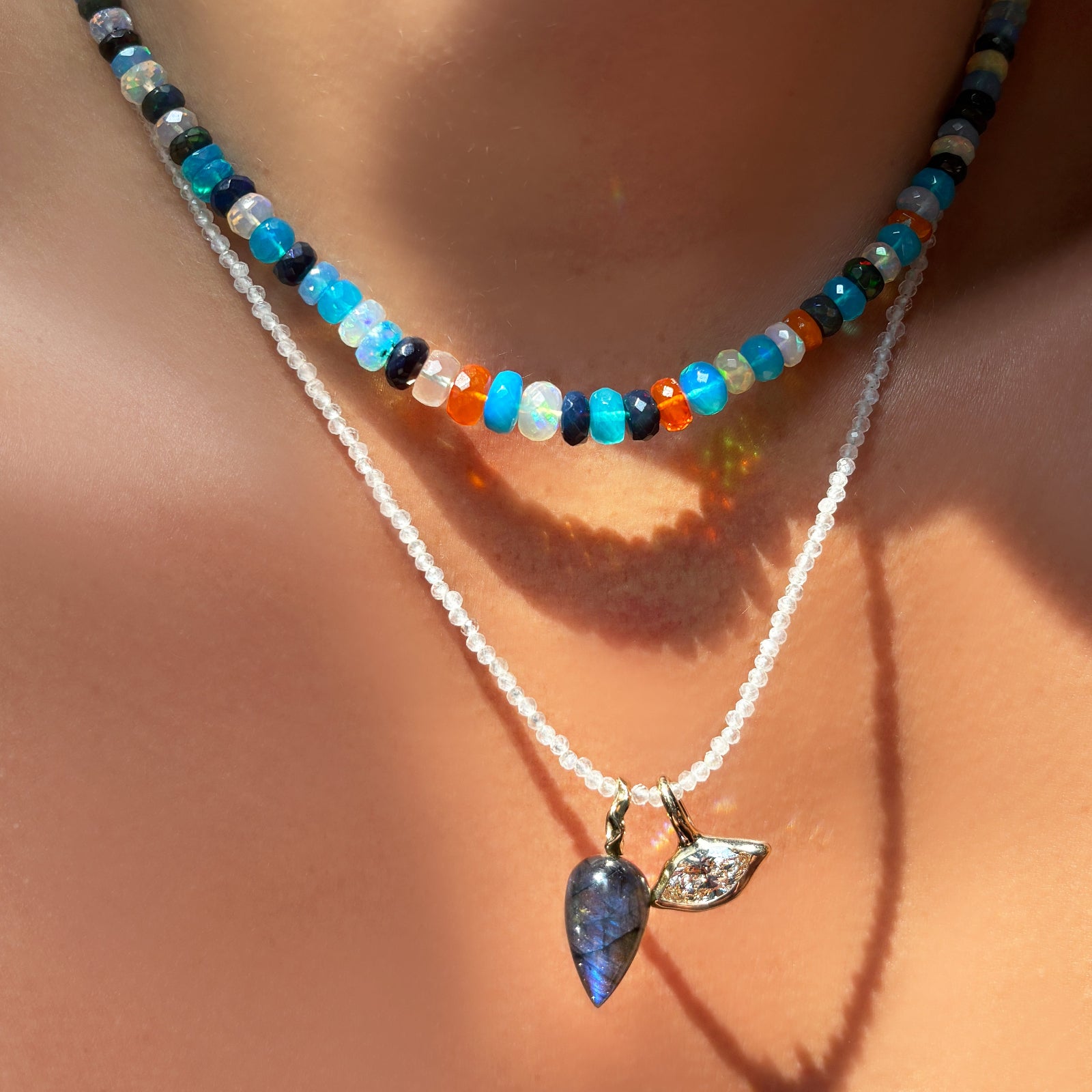 jaipur jazz faceted opal necklace layered over a moonstone slim gemstone necklace with labradorite drop charm and molten solitaire charm with marquise diamond on the neck.