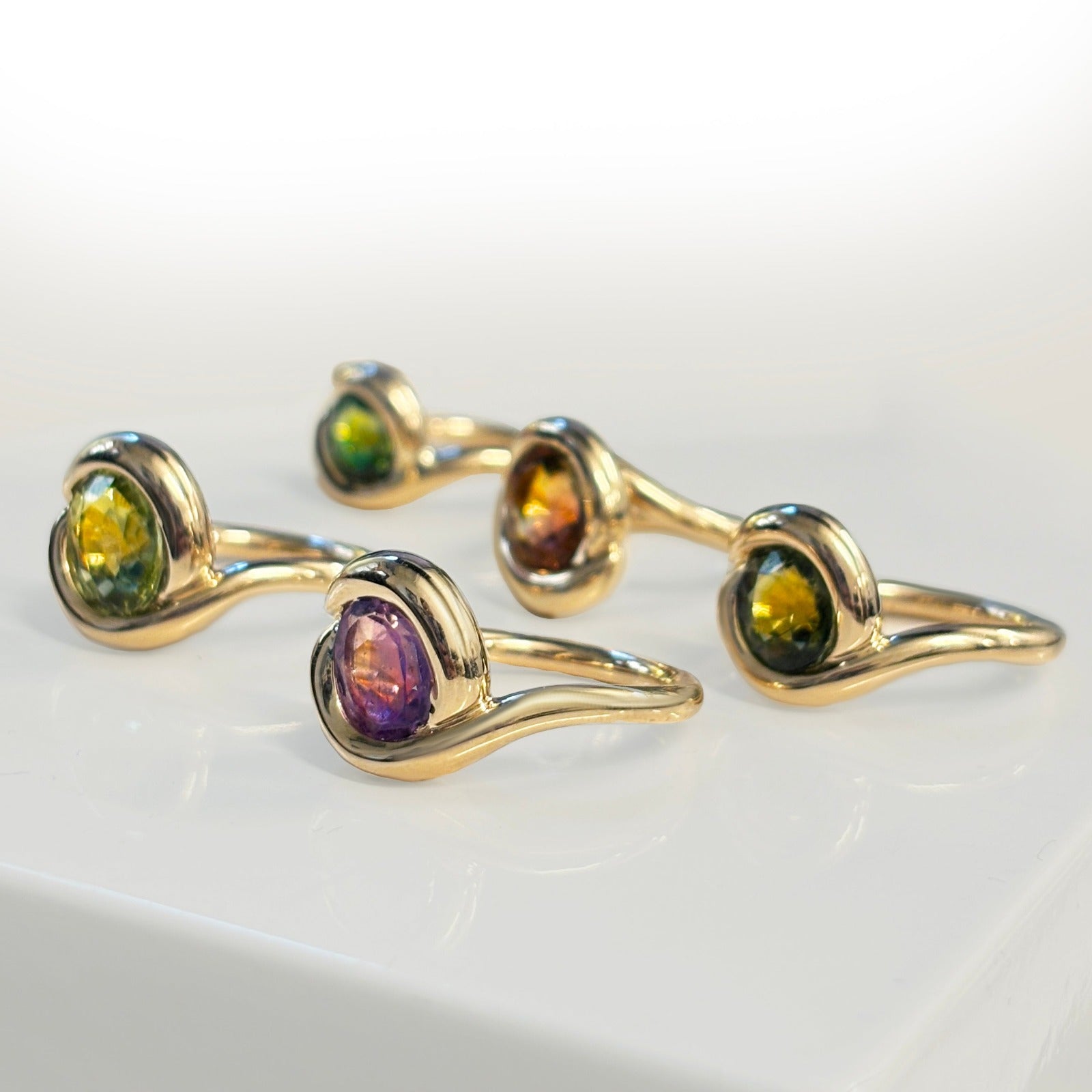 14k recycled gold Molten Knot Rings with Gemstones layered together on a white background