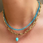 Amazonite acorn drop charm. Styled on a neck hanging from a beaded gold necklace with a blue opal necklace.