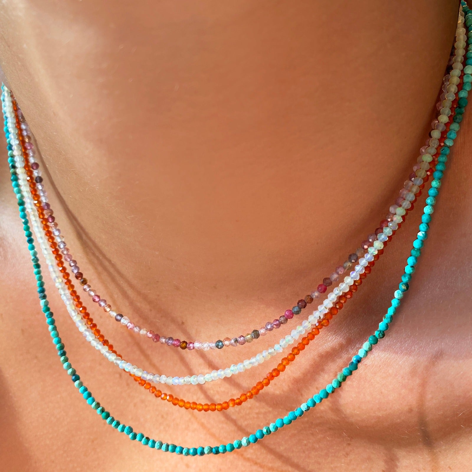 Four shimmering beaded slim gemstone necklaces made of 2mm faceted round stones in moonstone, tourmaline, carnelian and natural turquoise on a gold linking lobster clasp