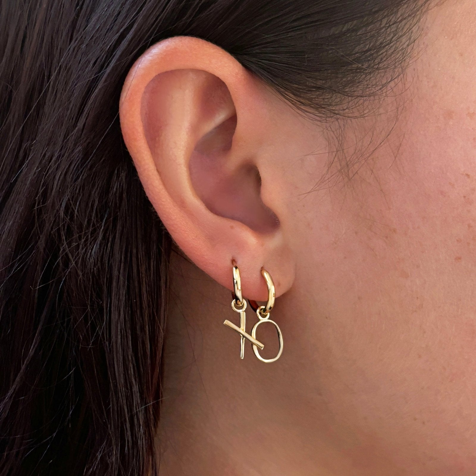 14K Recycled Gold Letter "X" and "O" Huggie on an ear