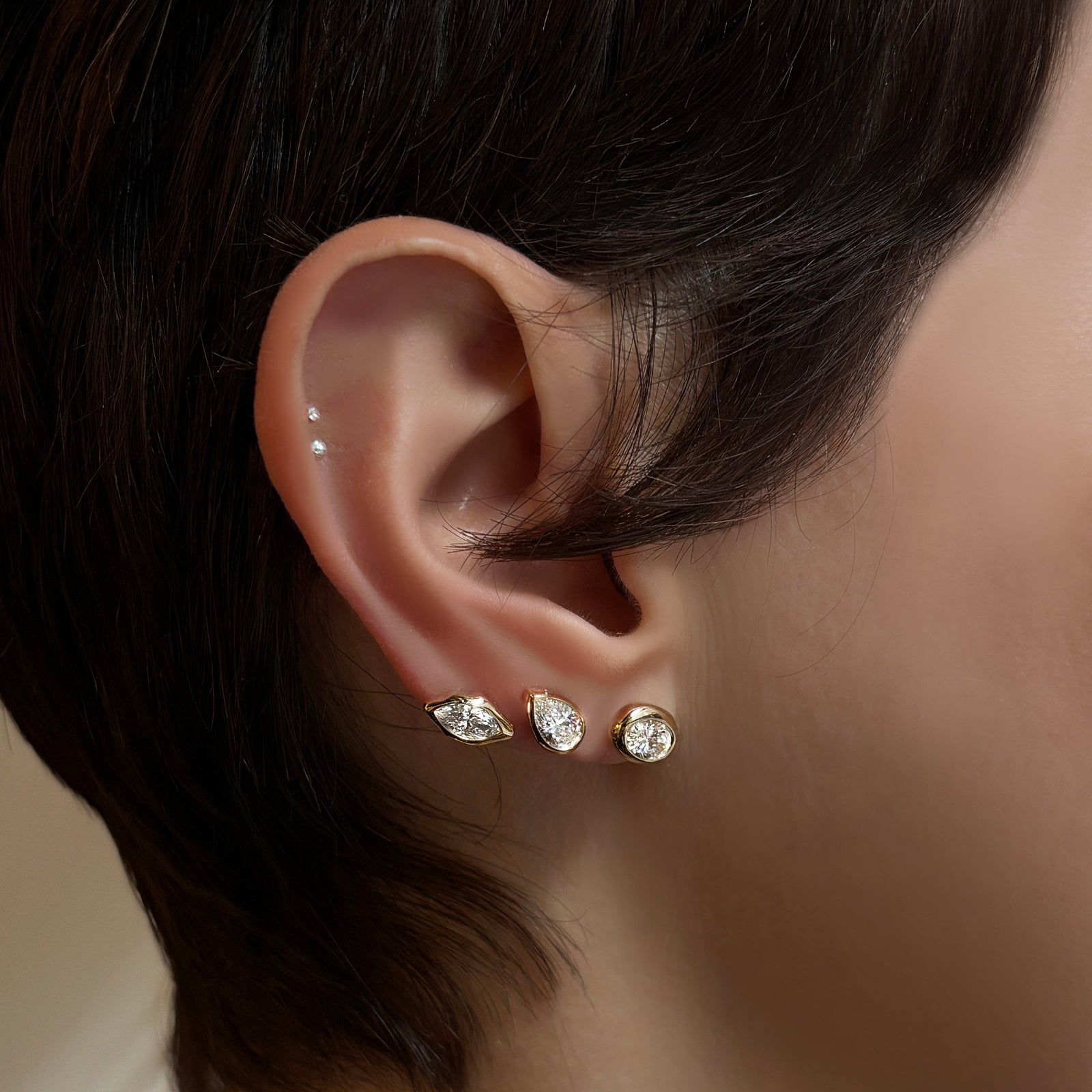 Marquise, pear, and oval molten solitaire diamond studs up the ear.