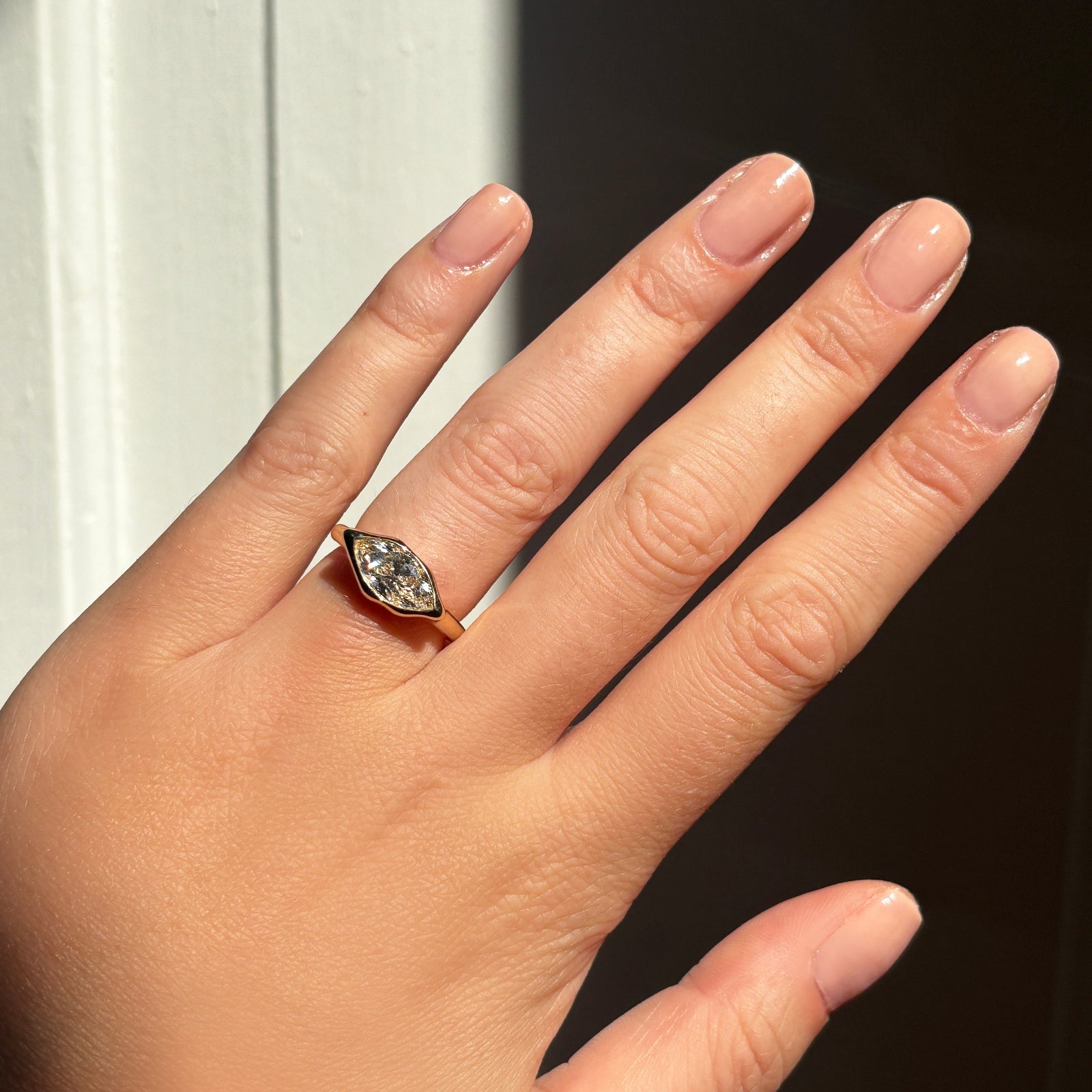 marquise molten solitaire ring on the hand with shadows behind.