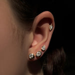 Molten solitaire stud earrings up the ear in round, oval, pearl, and marquise shapes set in 14k yellow gold.