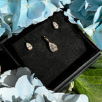 Molten Solitaire Pear Charm and Stud Earrings in a gift box with flowers.