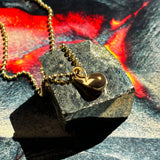 14k recycled Gold Molten Drop Charm on a gold bead chain layered over a molten lava image