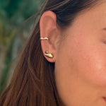 Liquid 14K Recycled gold round small molten stud earring on an ear layered with multiple gold earrings including the Molten Stud and Molten Midi Cuff