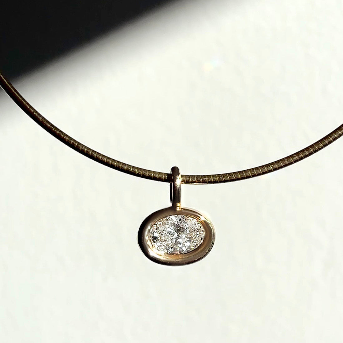 Recycled 14k yellow gold molten solitaire charm with oval diamond, hanging from an omega choker.