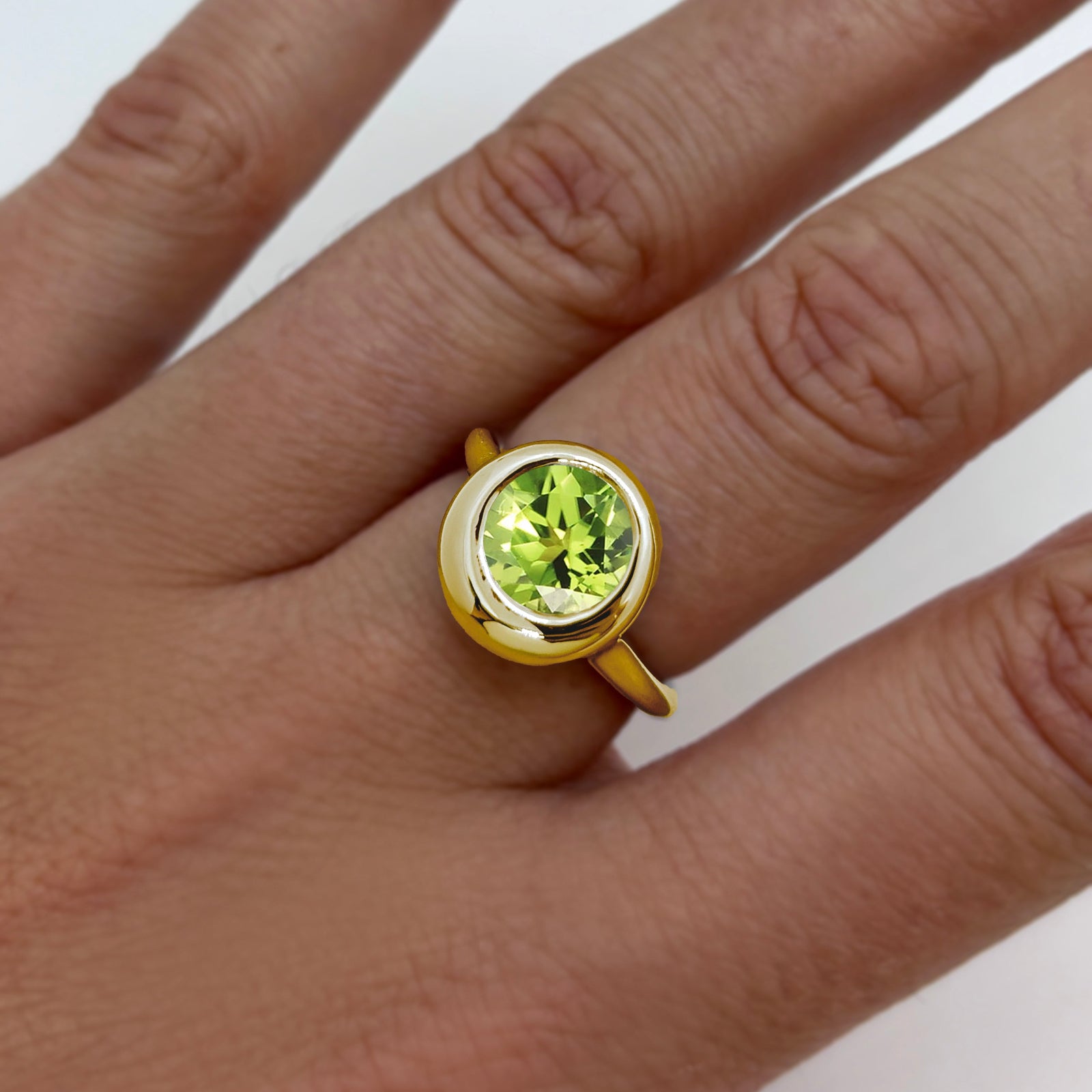AMANDA PEARL recycled 14k gold Molten Solitaire Ring with peridot gemstone on a model's hand.