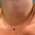Omega chain with molten knot charm with round rose cut ruby on the neck.