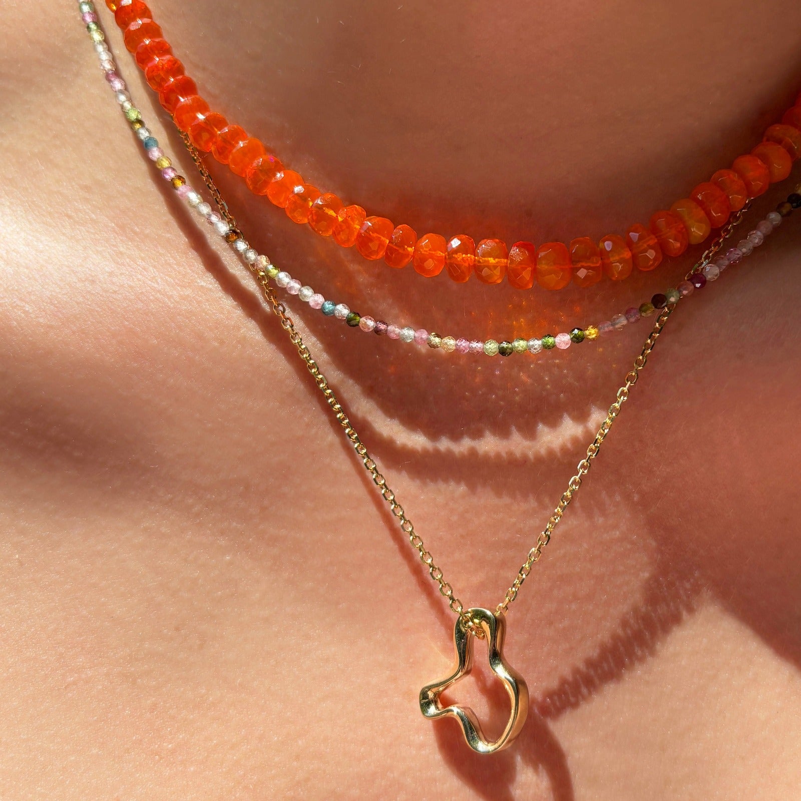 14k recycled gold Plain Ripple Charm. Hanging from a diamond cut cable chain necklace layered with a Tourmaline Slim Gemstone necklace and Orange Faceted Opal Necklace