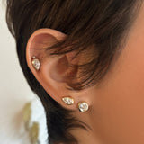 pear and round molten solitaire studs on the ear