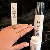 Shinery skincare product with applicator and packaging on a dark background