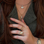 Layered mixed metal look with solitaire charms, ripple rings, and a molten knot ring paired with a Cartier Santos watch.