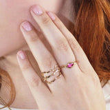A model wears a stack of 14k Recycled yellow Gold Ripple Rings studded with small sustainable lab grown diamonds on her pointer finger. On her middle finger she wears a marquise tourmaline ripple ring, with a large pink tourmaline in the center. 