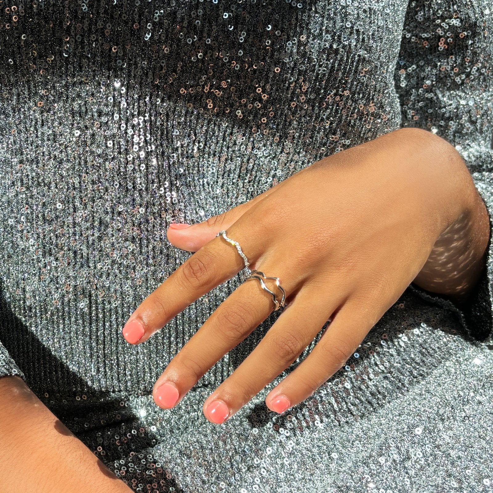 A model in a sparkly silver outfit. Set of three ripple rings in 14K recycled white gold, set with pavé ethical, lab grown diamonds.
