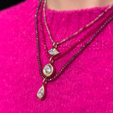 ruby, pink spinel, purple garnet slim gemstone necklaces with molten solitaire charms with diamonds worn over a bright pink sweater.