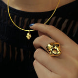 14K recycled yellow gold choker with skull charm, with a skull ring styled on a hand