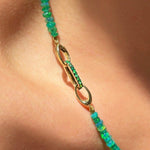 14k gold Small Diamond Charm Lock with emerald pavé on a white background styled on a neck locked onto oval clasps of a Green Faceted Opal Necklace.