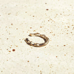 14k recycled gold Ripple Midi Ear Cuff on a stone surface