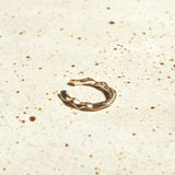 14k recycled gold Ripple Midi Ear Cuff on a stone surface