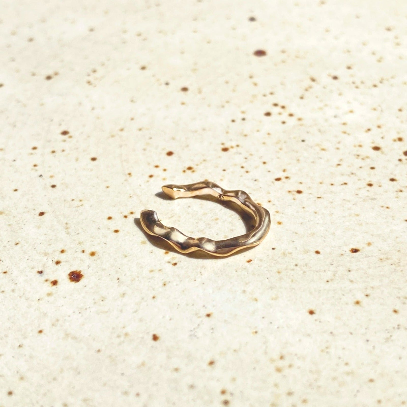 14k recycled gold Ripple Midi Ear Cuff on a stone surface