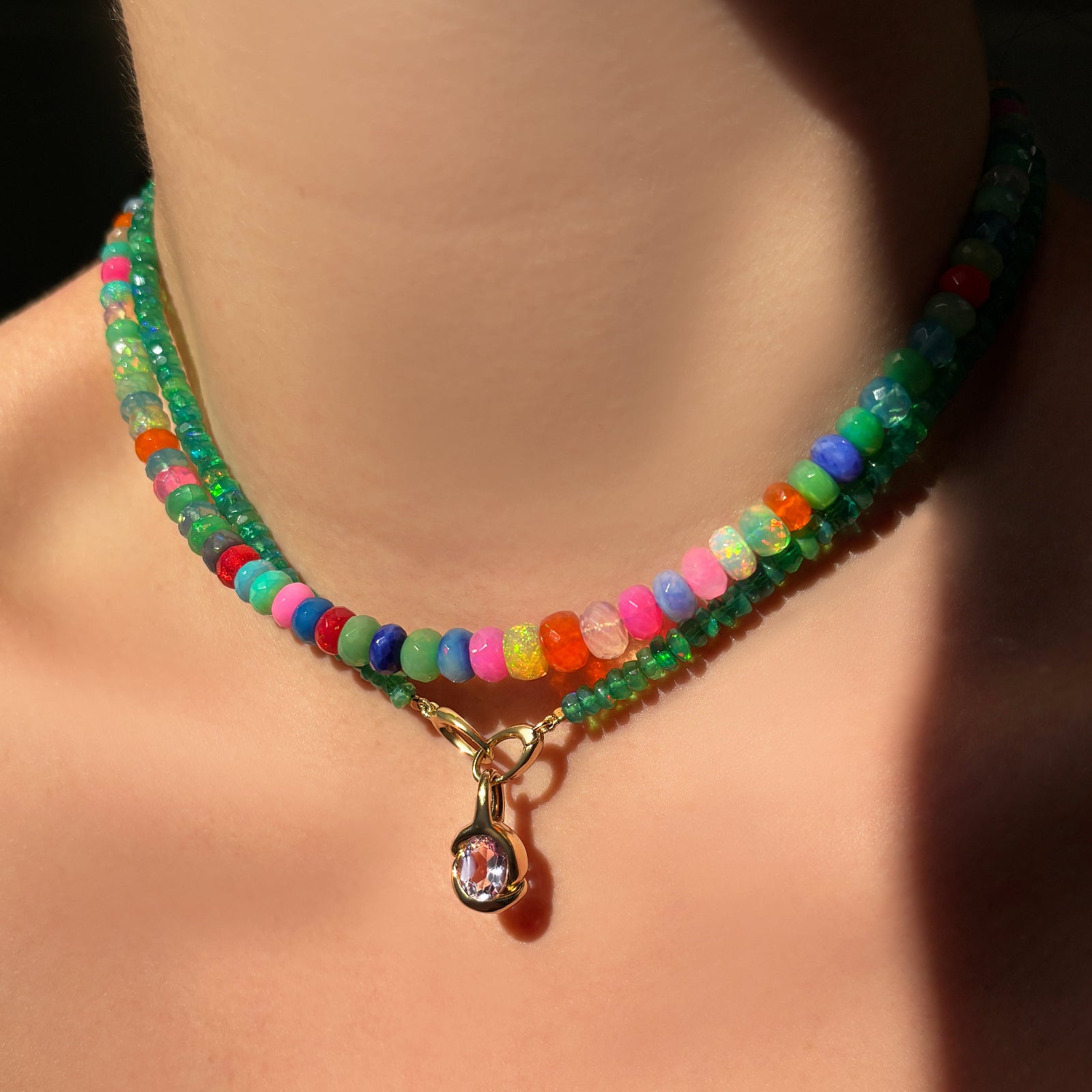 Colorful faceted opal necklace layered with a green faceted opal necklace and a 14K recycled yellow gold molten amethyst knot charm hanging from the clasp at the front.