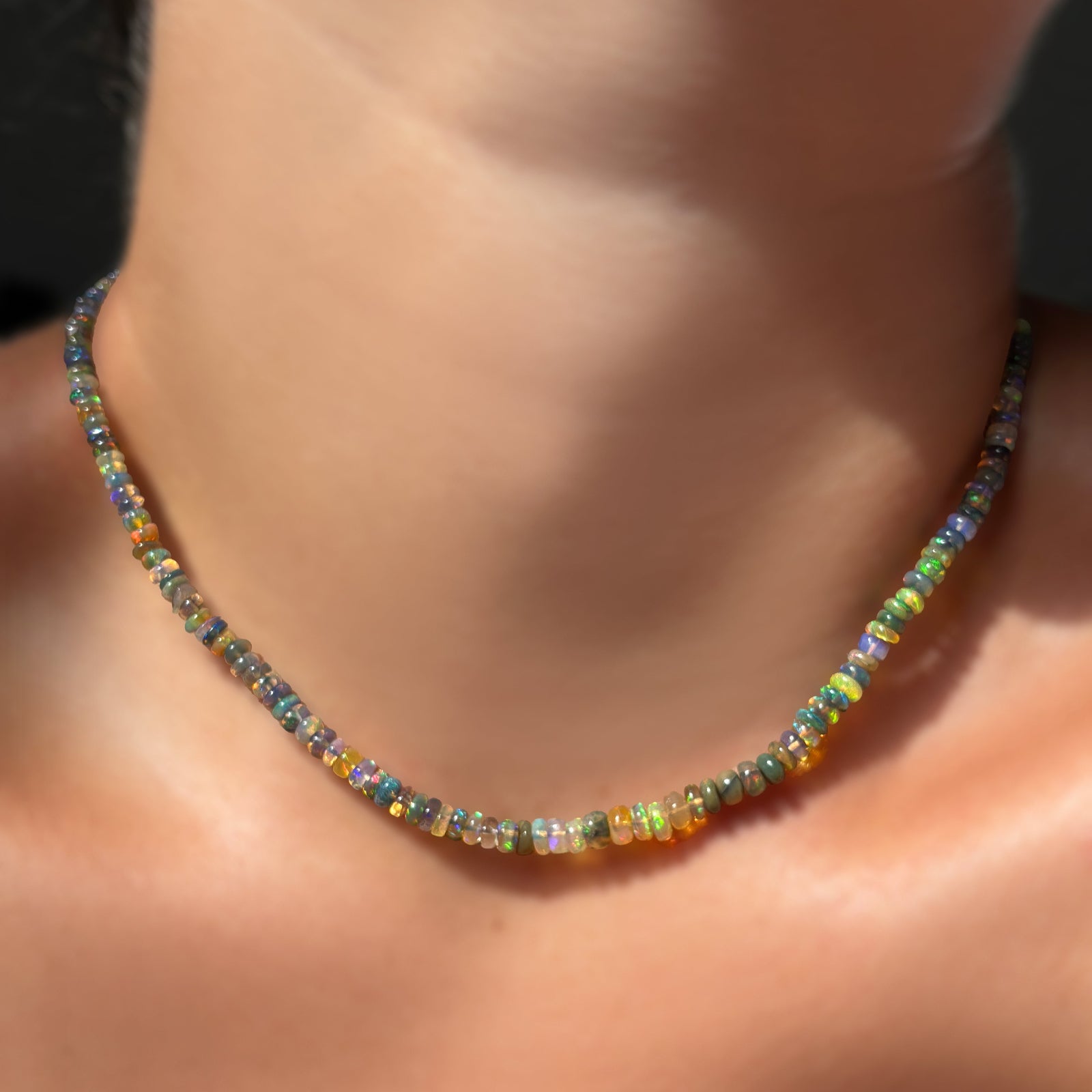 A single Tide Pool Opal Necklace on bare skin in the sunlight.