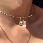 Wire choker with molten solitaire charm with pear-cut cultivated diamond and faceted rose quartz drop charm on ripple bale in recycled 14k gold on a model's neck.