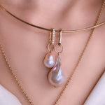 14k gold small oval locking charm with diamond pavé detail. Styled on a neck with a wire choker necklace and baroque pearl charms.
