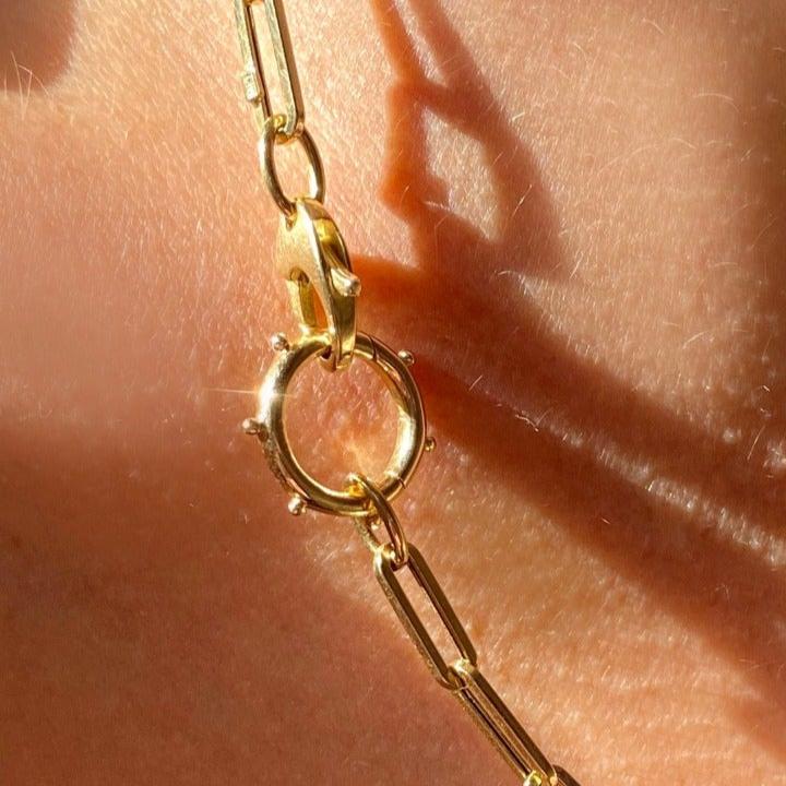 14k recycled yellow gold Beaded Round Charm Lock styled on a neck locked onto lobster clasps of a paperclip chain necklace.